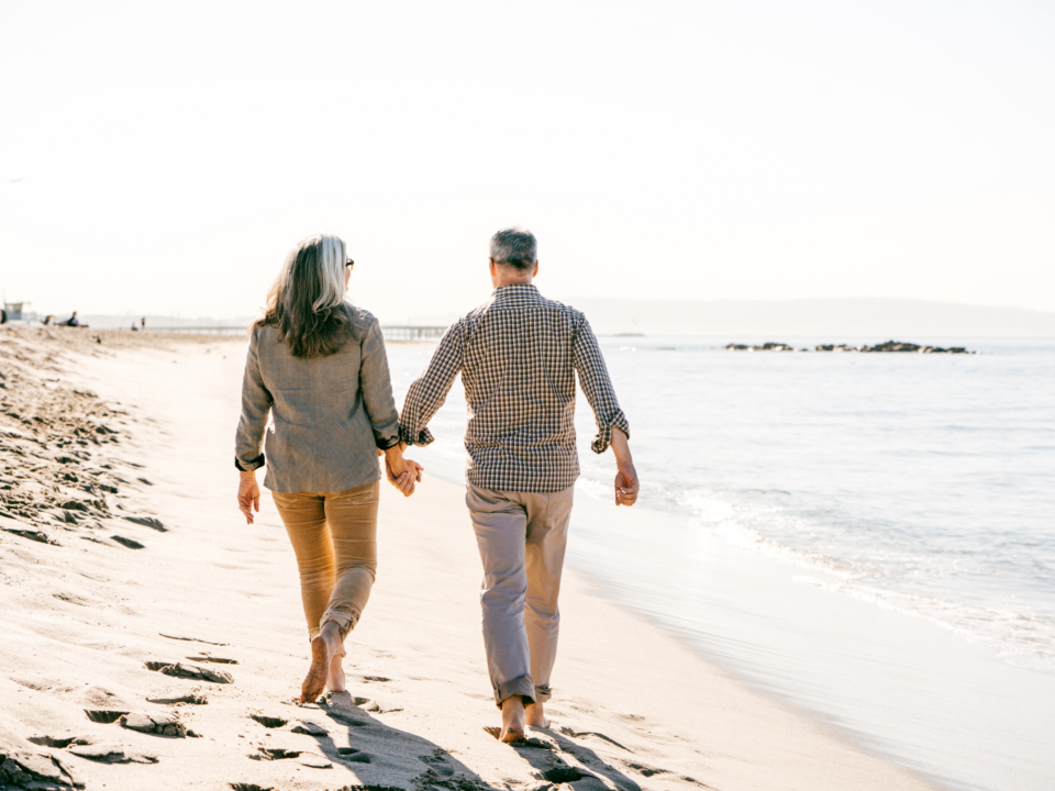 Life insurance customers walking on the beach holding hands