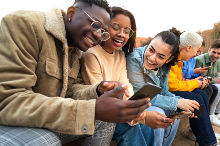 group of young people browsing their phones and looking happy